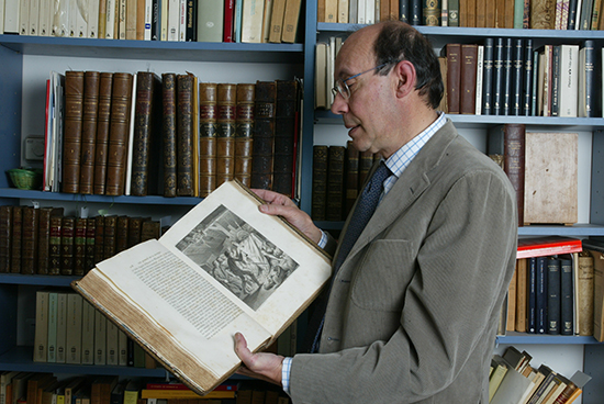 Francisco Rico ojeando una edición   ilustrada del Quijote en su biblioteca personal (Fotografía de María   José Rasero).